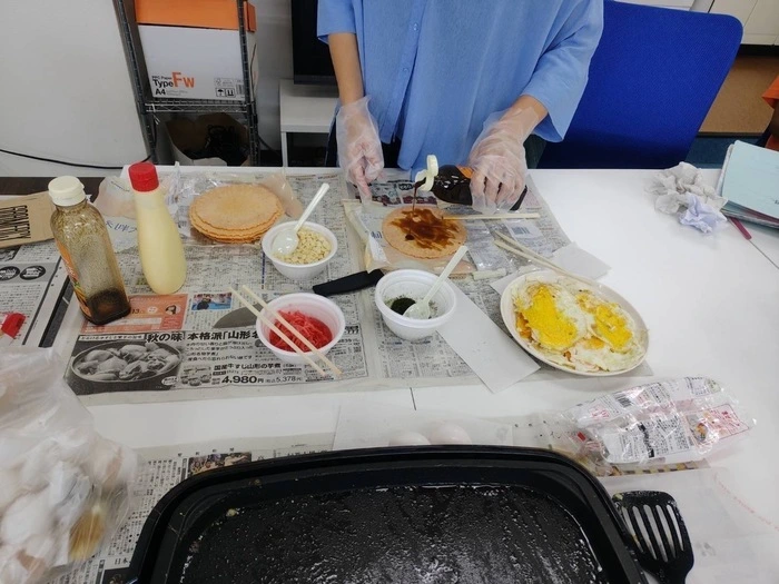 たません作りでえびせんにソースをかけている様子